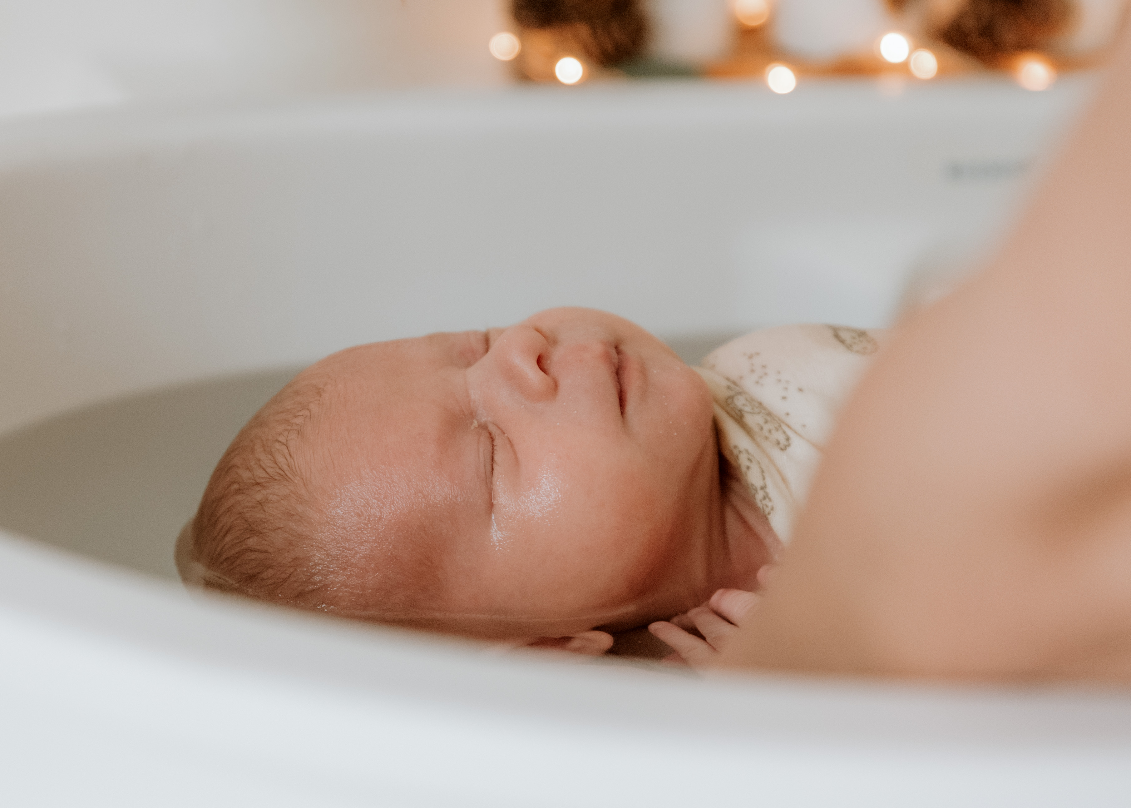 Nouveau-né apaisé, enveloppé dans son lange pendant le bain, les yeux fermés · Entre Deux