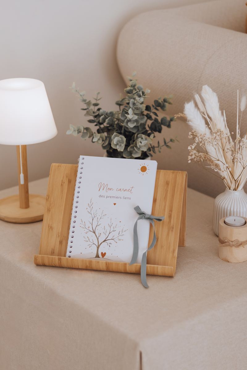 Le carnet des premiers liens posé sur un pupitre de bois, près d'une lampe et d'un bouquet d'eucalyptus — Entre Deux