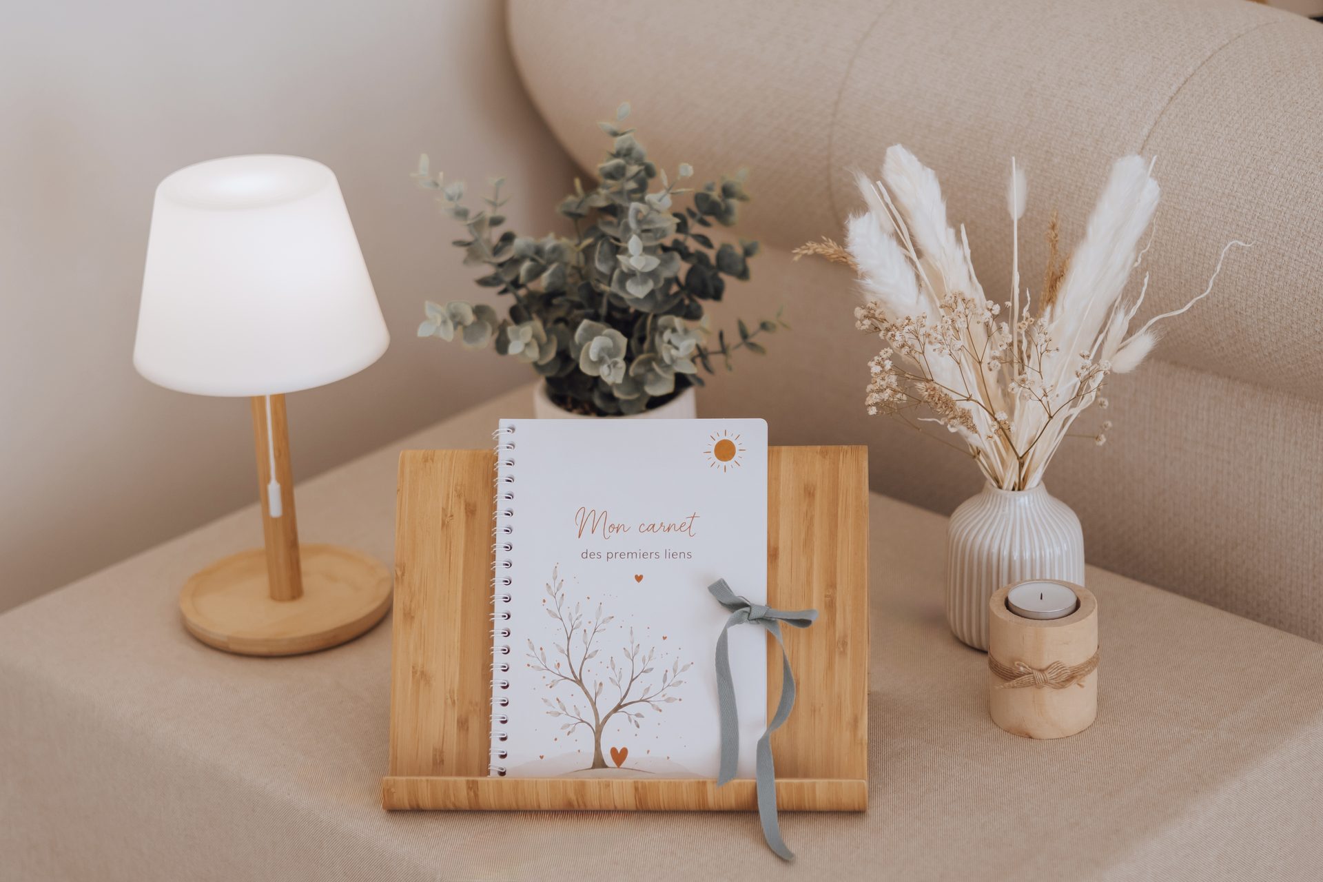 Carnet de grossesse ouvert sur une table, entouré de bougies et de fleurs séchées — Entre Deux