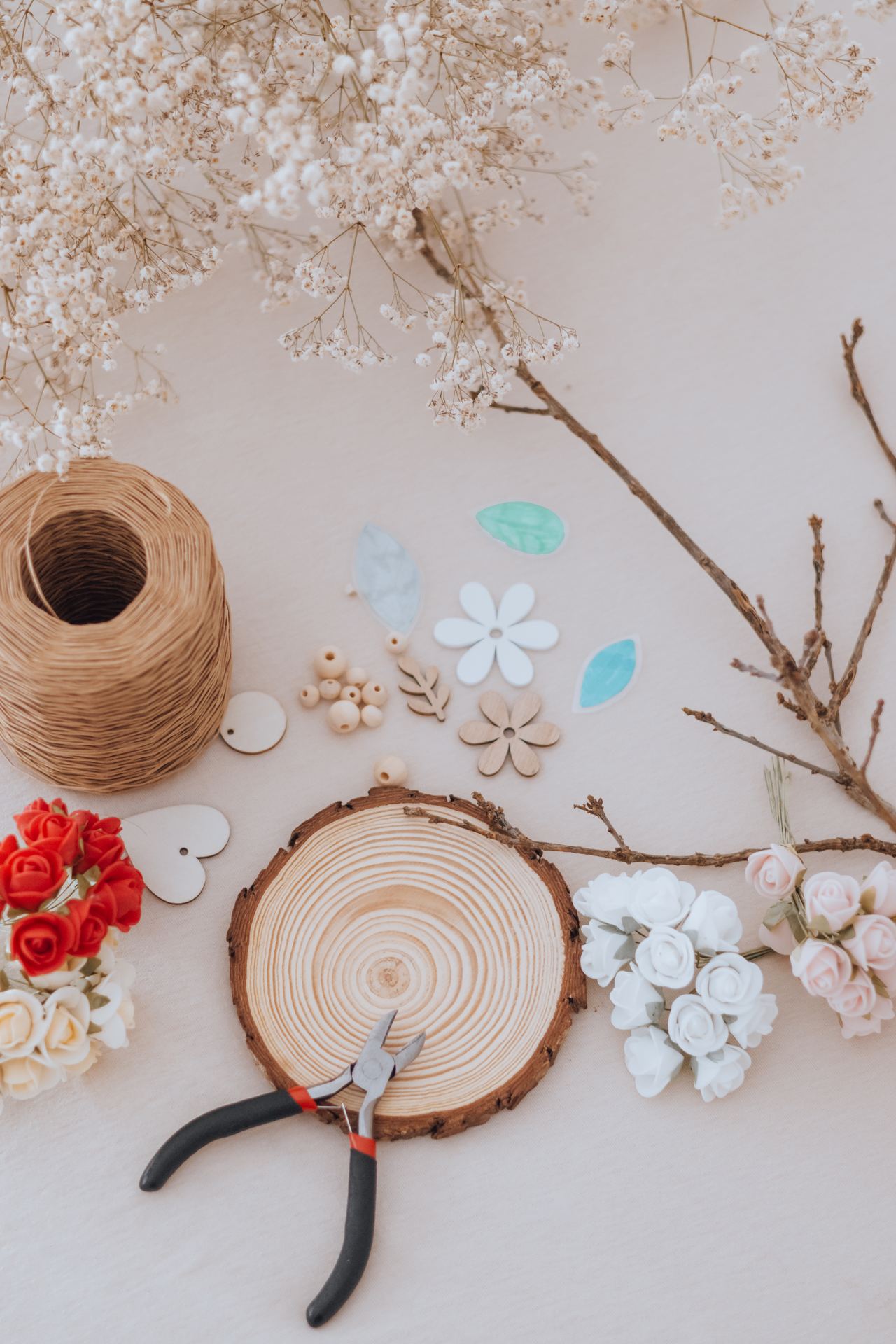 Matériel de l'atelier disposé sur la table : branche, rondin de bois, ficelle, perles et fleurs séchées — Entre Deux