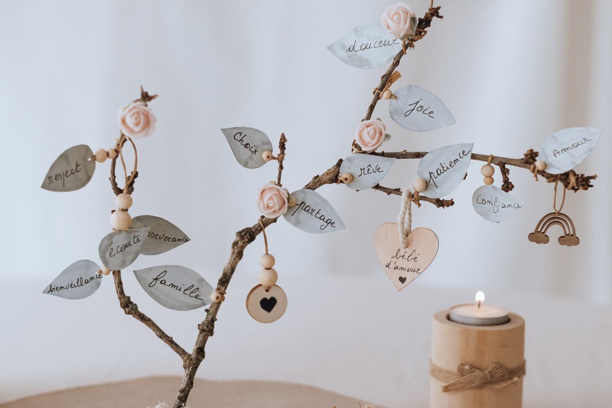 L'arbre des valeurs de près : ses feuilles calligraphiées, son arc-en-ciel et ses cœurs de bois, éclairés par une bougie — Entre Deux