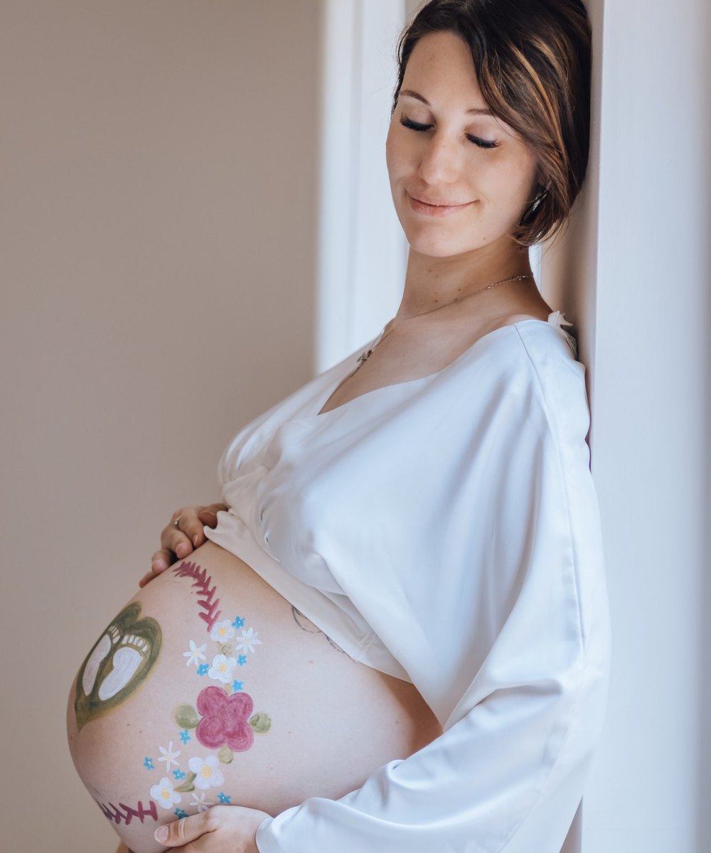 Future maman souriante, son ventre peint de fleurs bleues — Entre Deux