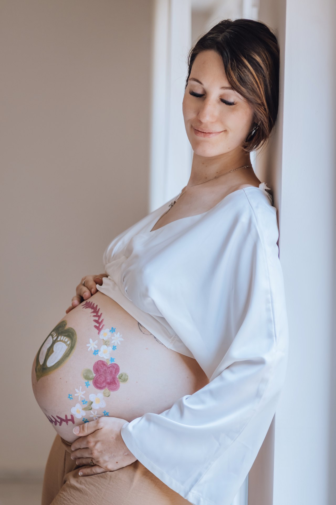 Future maman les mains posées sur son ventre peint de fleurs