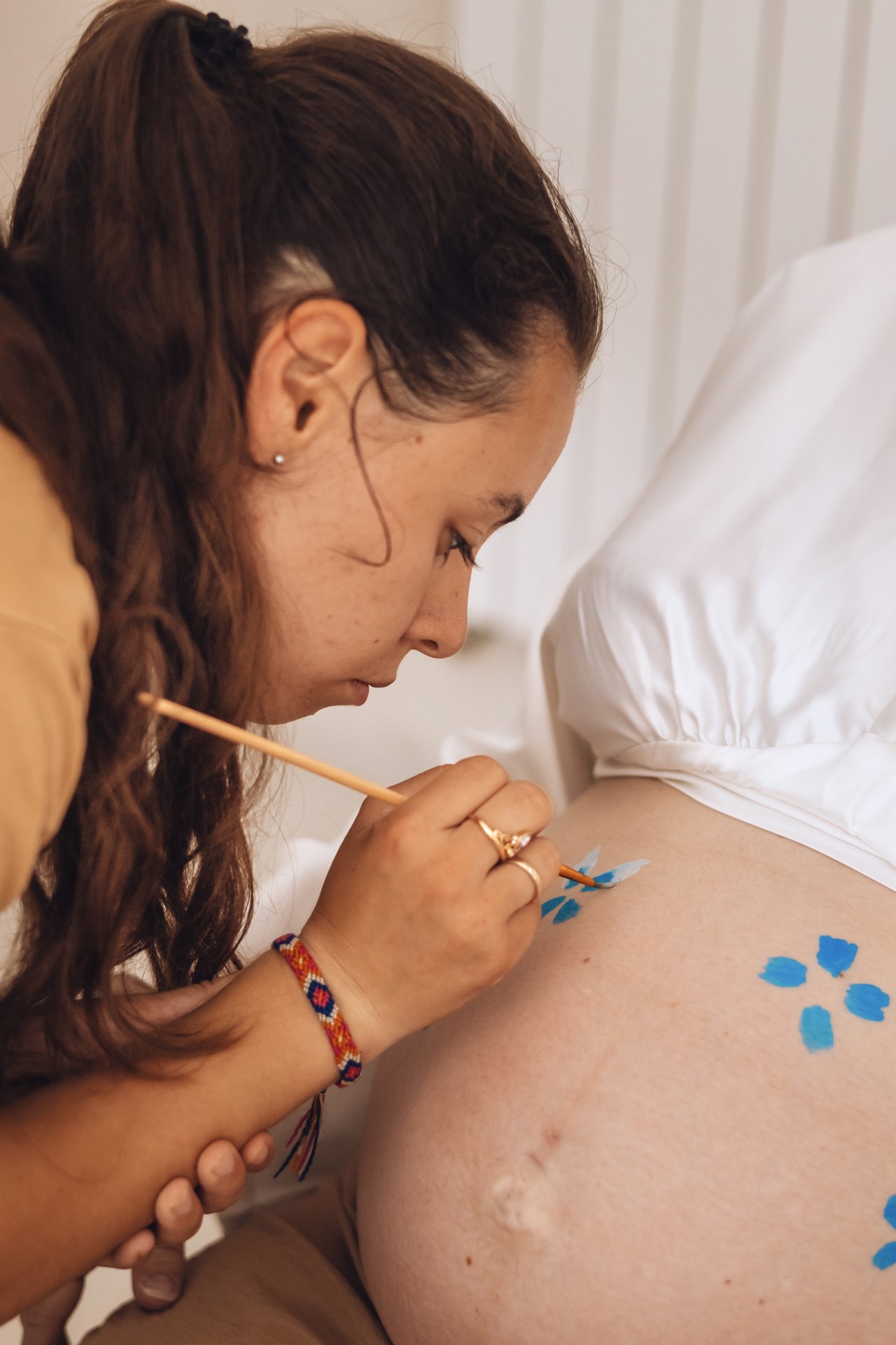 Stéphanie peint délicatement le ventre d'une future maman