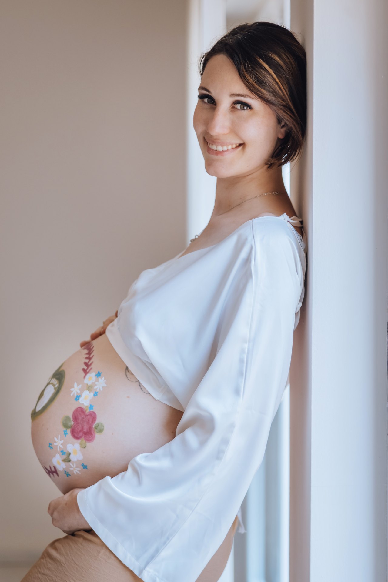 Portrait souvenir d'une future maman souriante au ventre peint