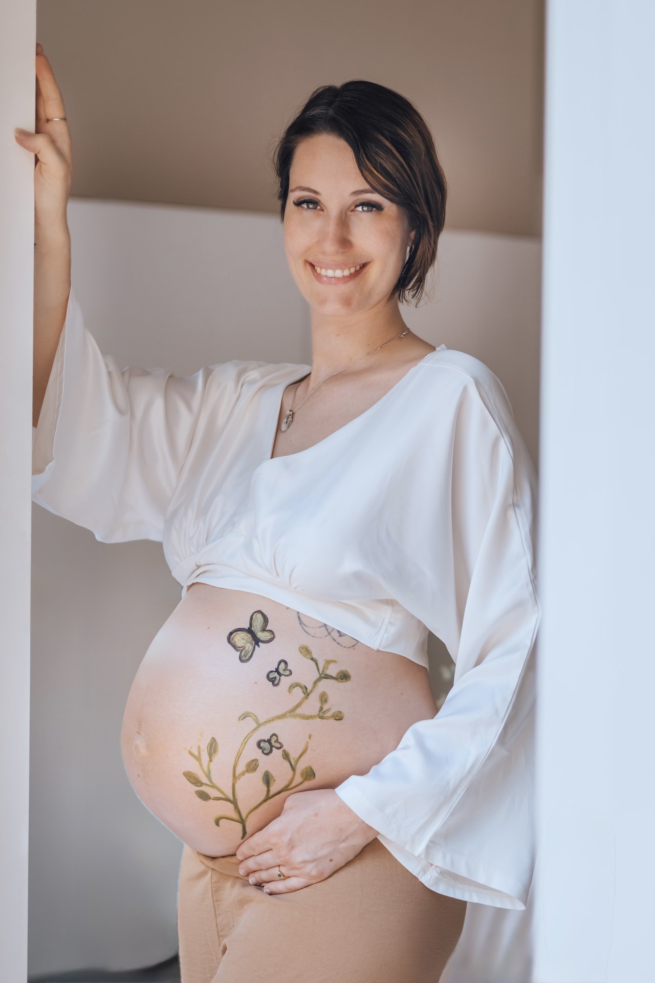 Séance photo souvenir : future maman debout, ventre peint de fleurs