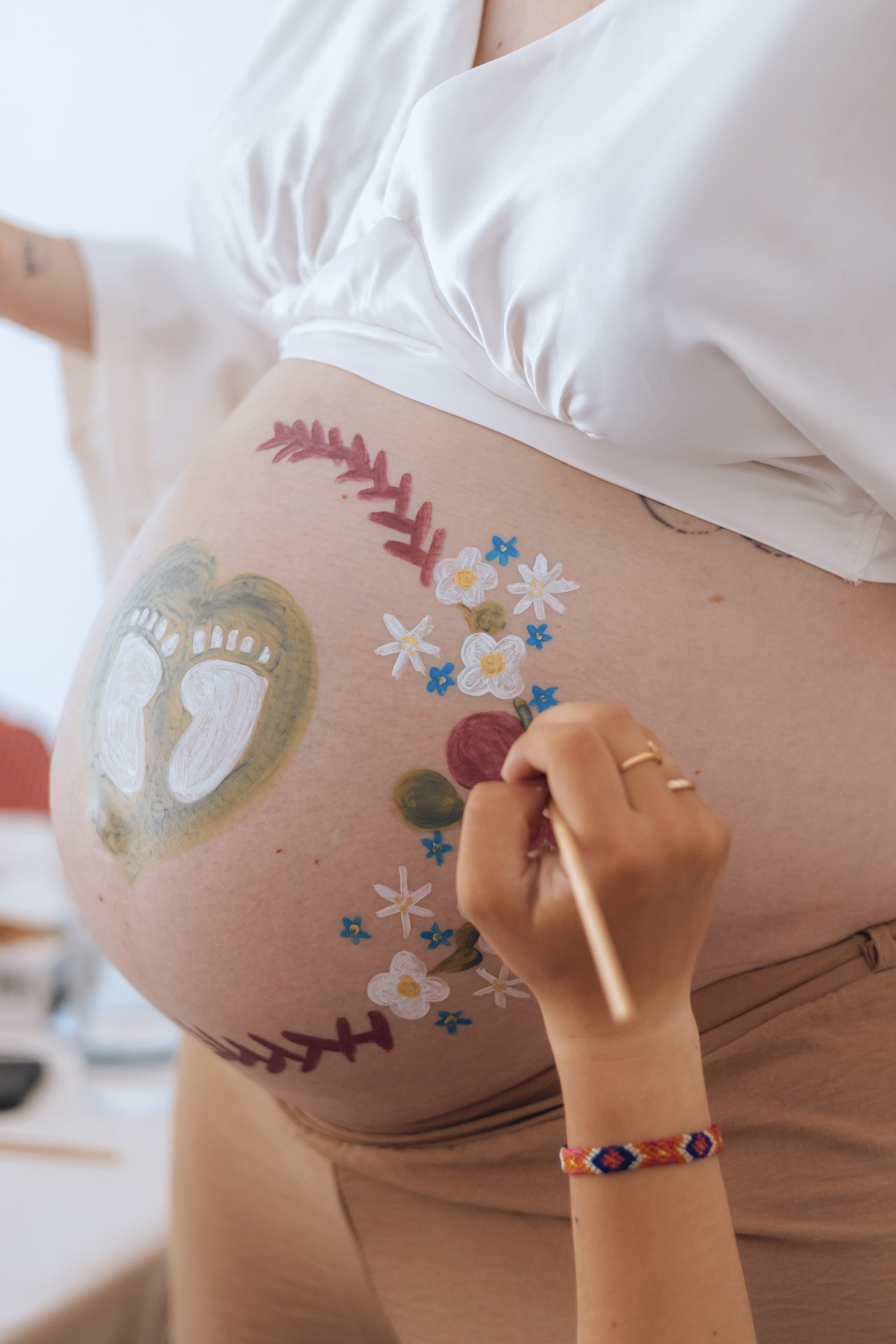 Guirlande de fleurs peinte sur le ventre d'une future maman