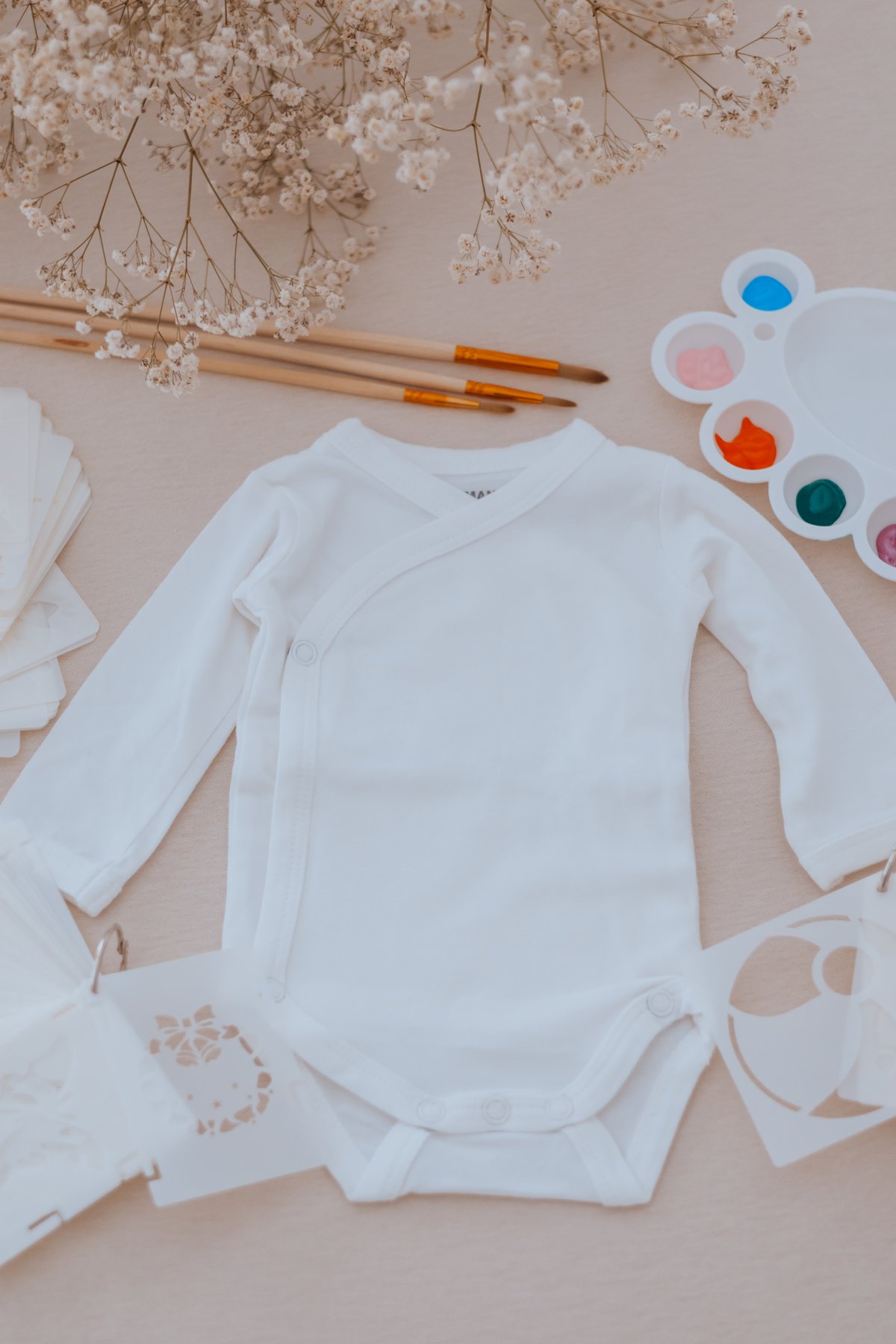 Body de bébé, pinceaux, palette et pochoirs pour peindre pendant l'atelier — Entre Deux