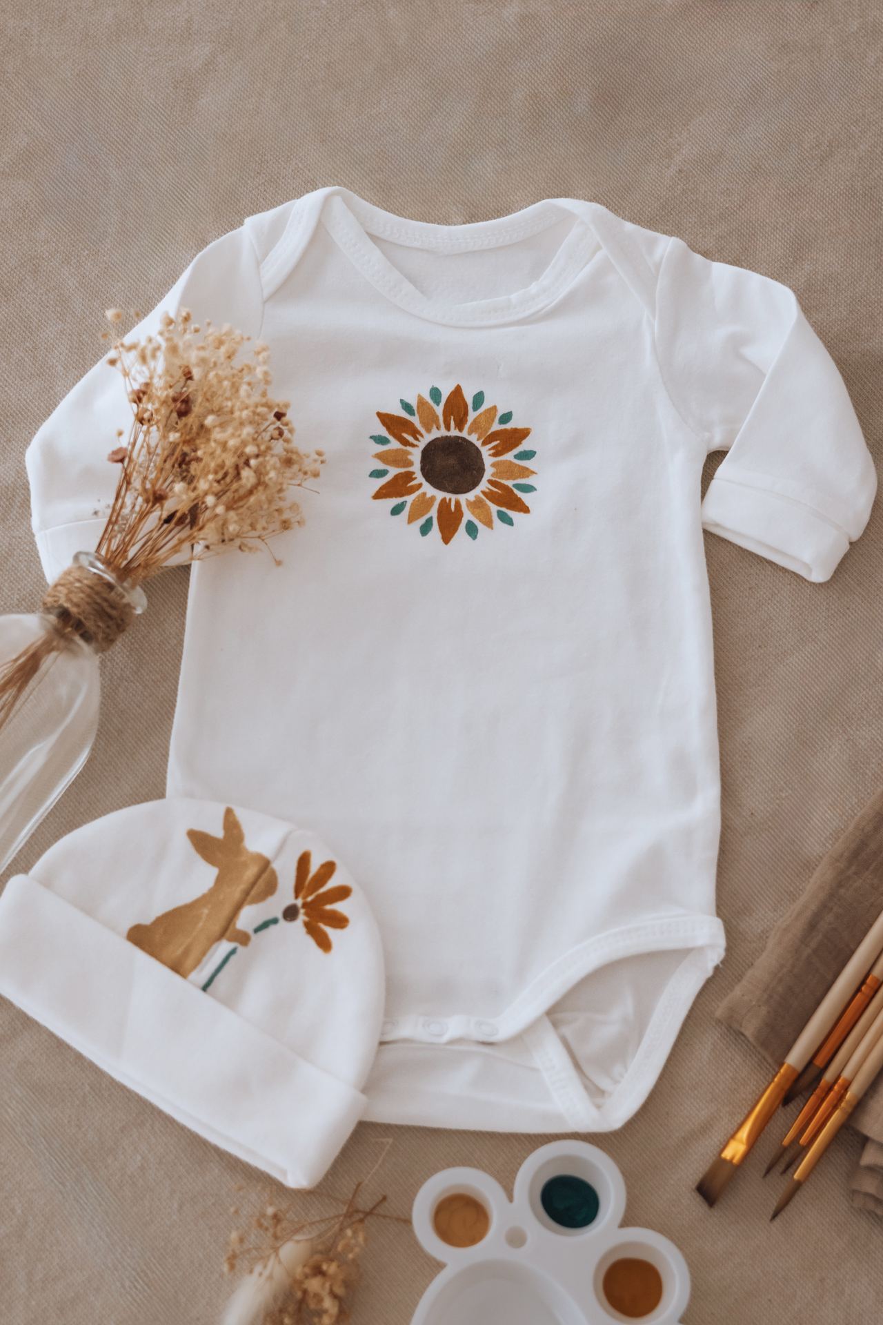 Fleur peinte à la main sur un vêtement de bébé, séché sur un tissu clair