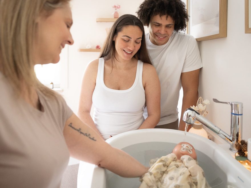 Les deux parents et Stéphanie penchés au-dessus du bain enveloppant de leur bébé — Entre Deux, Enghien