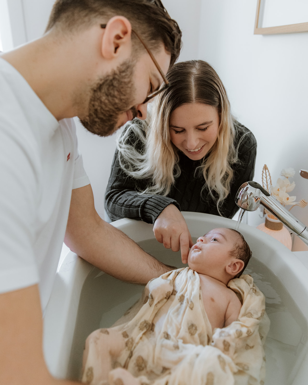 Parents penchés sur le bain enveloppant de leur nouveau-né — Entre Deux