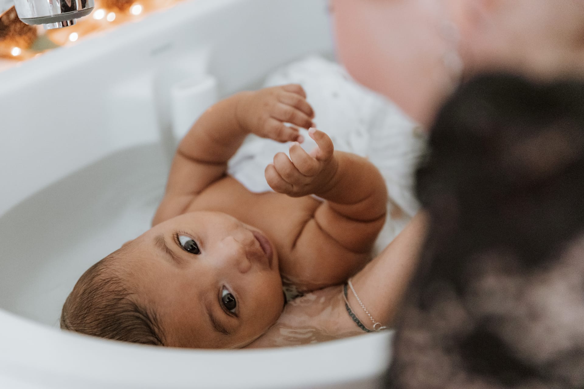 Bébé regardant la caméra pendant son bain enveloppant — Entre Deux