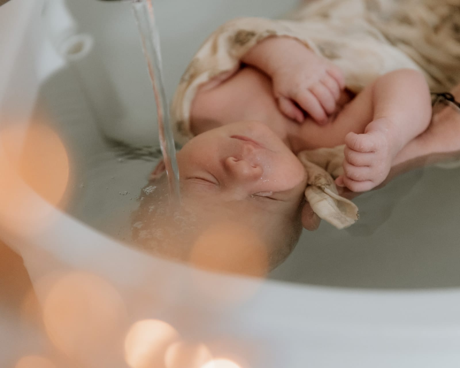 Bébé endormi sous un filet d'eau lors du bain enveloppant — Entre Deux