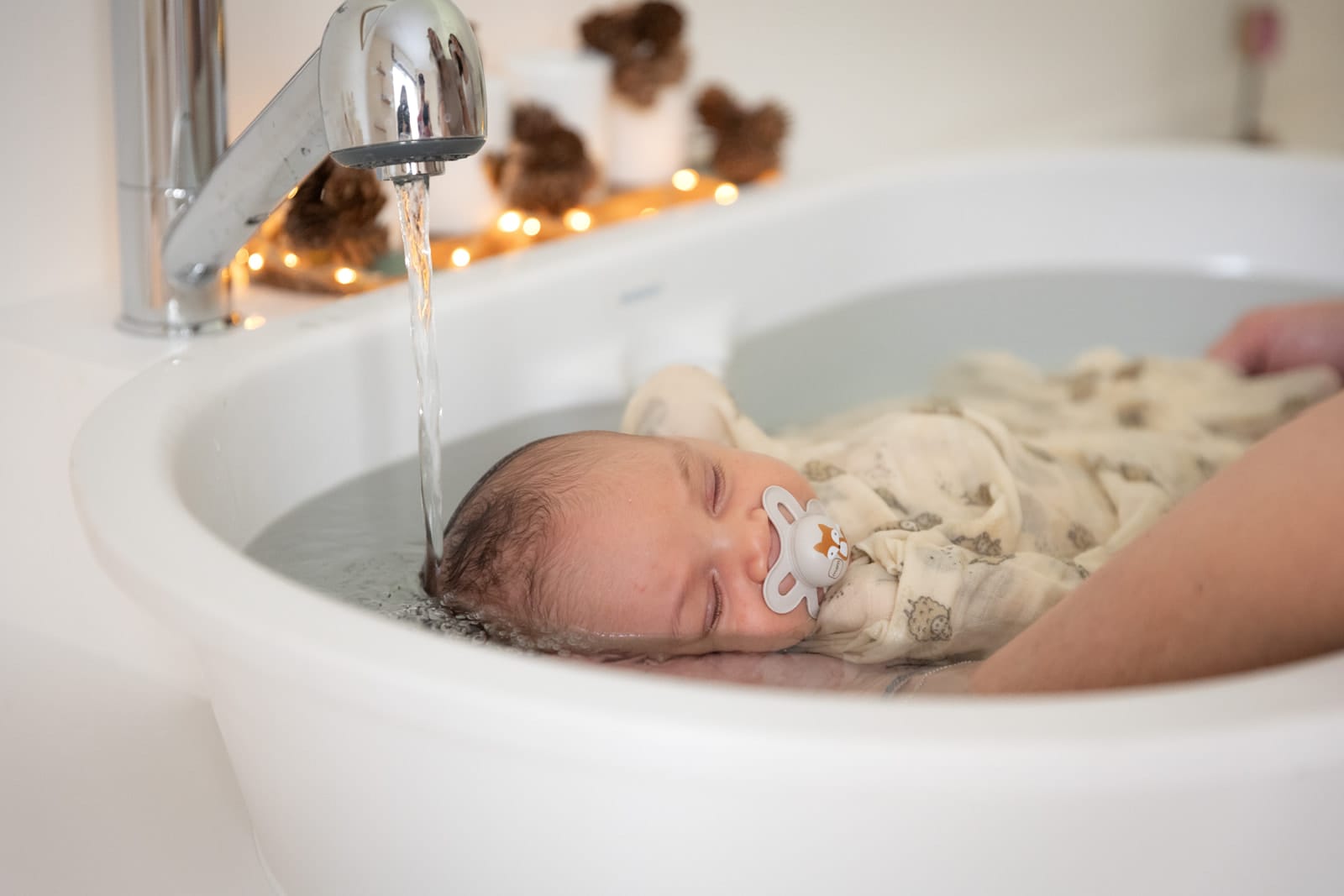 Nouveau-né bercé sous le robinet pendant le bain enveloppant — Entre Deux