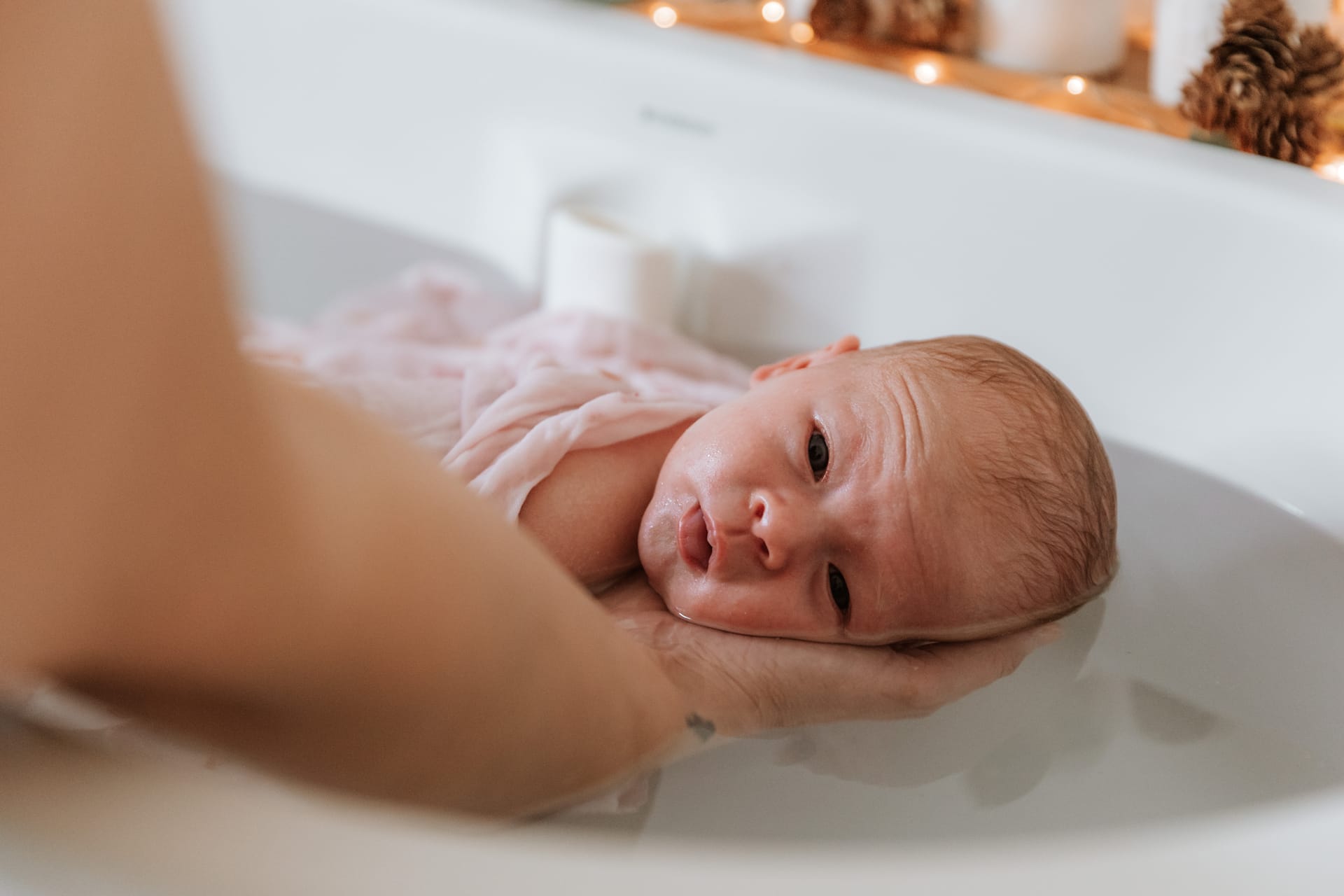 Nouveau-né dans un lange rose pendant le bain enveloppant — Entre Deux